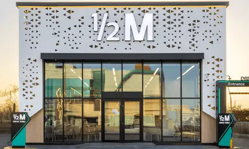 واجهة هاف مليون جدة مع جلسات خارجية وشباب يستمتعون بالقهوة والمشروبات.